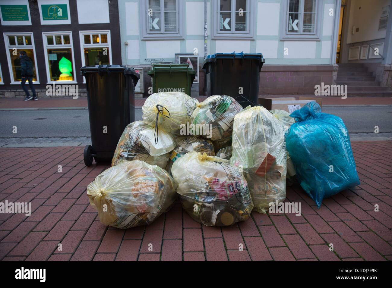 Großer Stapel von Plastikmülltüten außerhalb der Mülleimer auf gepflastertem Bürgersteig. Stockfoto