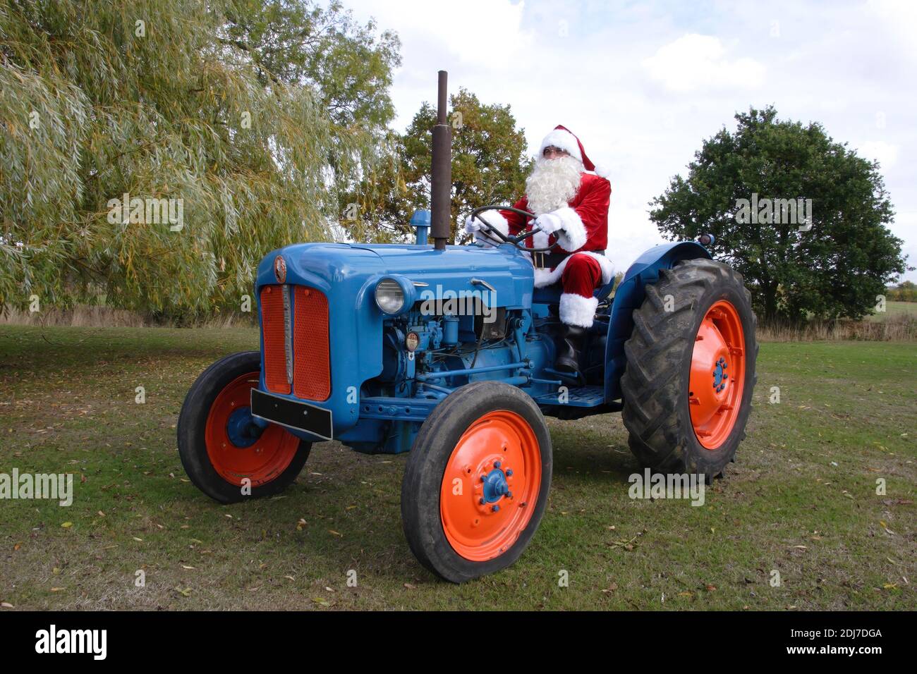 Vater Weihnachten fahren einen Fordson Dexta blauen Traktor in einem Wiese Stockfoto