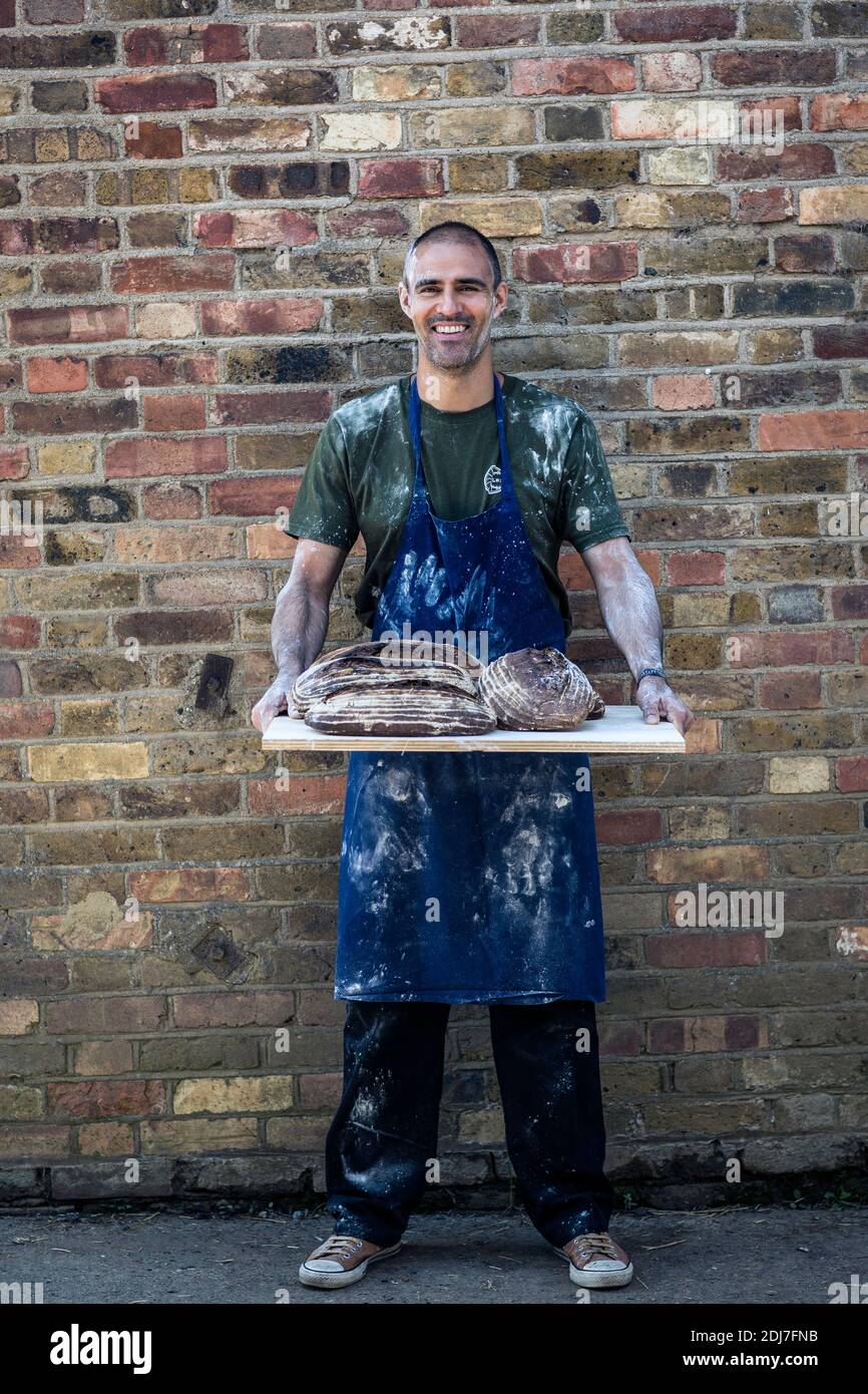 Handwerklicher Bäcker, der Brote hält Stockfoto