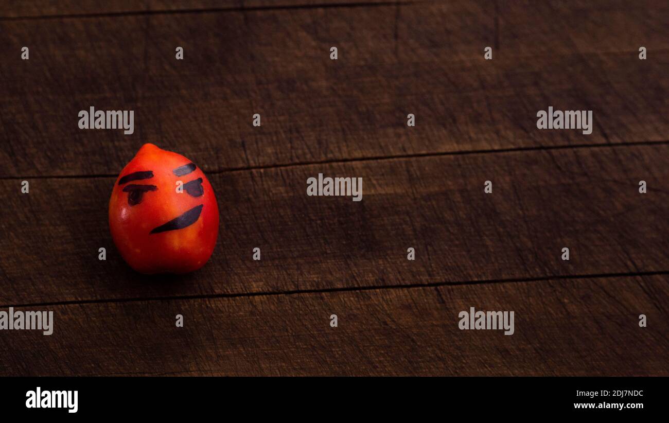 Ein paar Tomaten mit lustigen Gesichtern. Das Konzept einer gesunden Ernährung und Lebensstil. Isoliert auf einem hölzernen Hintergrund. Stockfoto