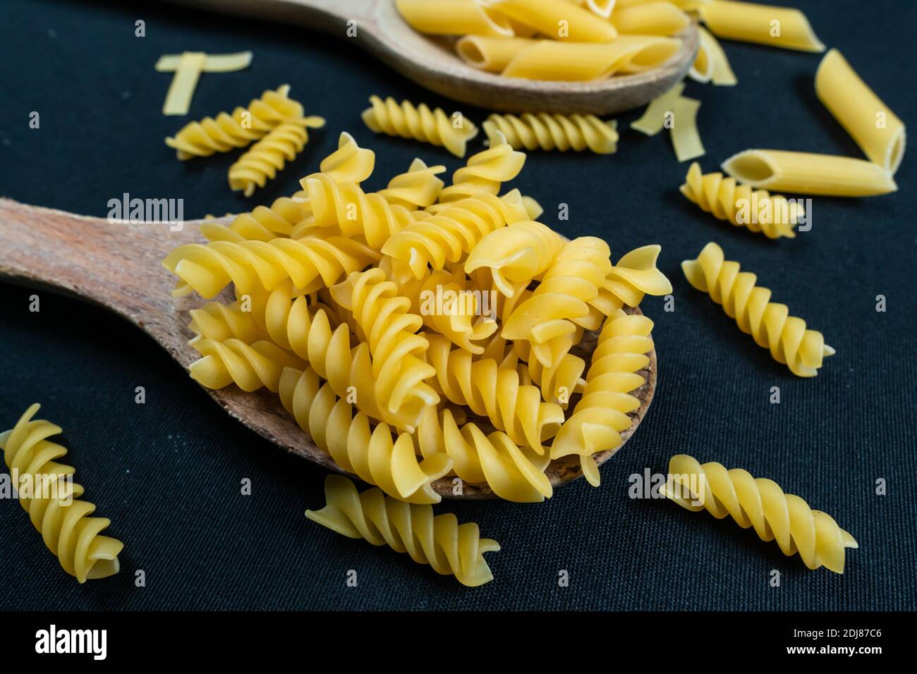 Verschiedene Arten von italienischen Pasta in Löffel auf der schwarzen Hintergrund Stockfoto