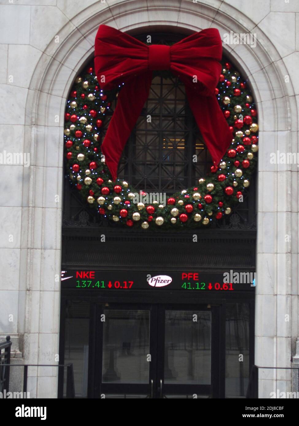 New York, New York, USA. Dezember 2020. 13. Dezember 2020 Wall Street vor der New Yorker Börse Anwohner und Touristen besuchen die Fearless Girl Statue und fotografieren am Weihnachtsbaum der Börse. New York Stock Exchange Ticker zeigt Pfizer Zitat Kredit: Bruce Cotler/ZUMA Wire/Alamy Live News Stockfoto