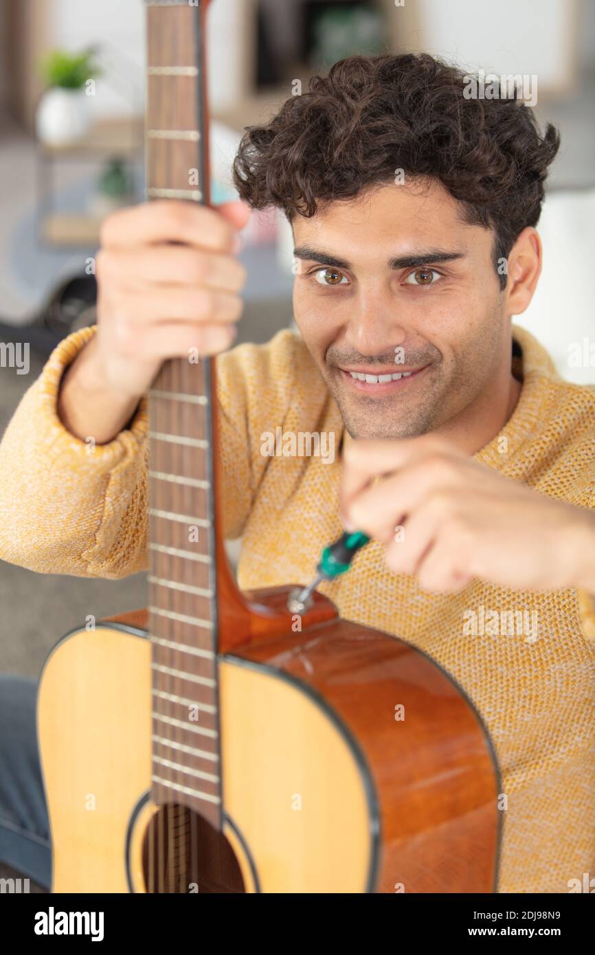 Junge gut aussehende Werkstatt Reparatur Gitarre Stockfoto
