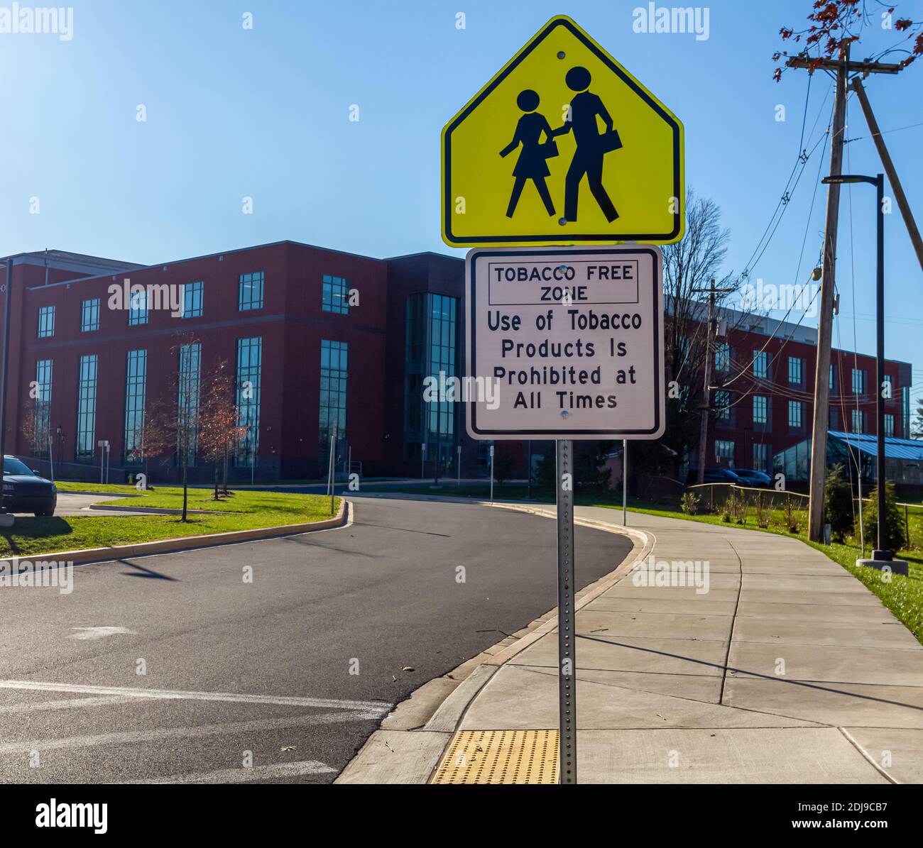 Tabaco Free Zone Schild mit Schülerkreuzung Schild vor einer öffentlichen High School in Maryland. Tabakerzeugnisse sind in den Räumlichkeiten nicht erlaubt, um s zu vermeiden Stockfoto