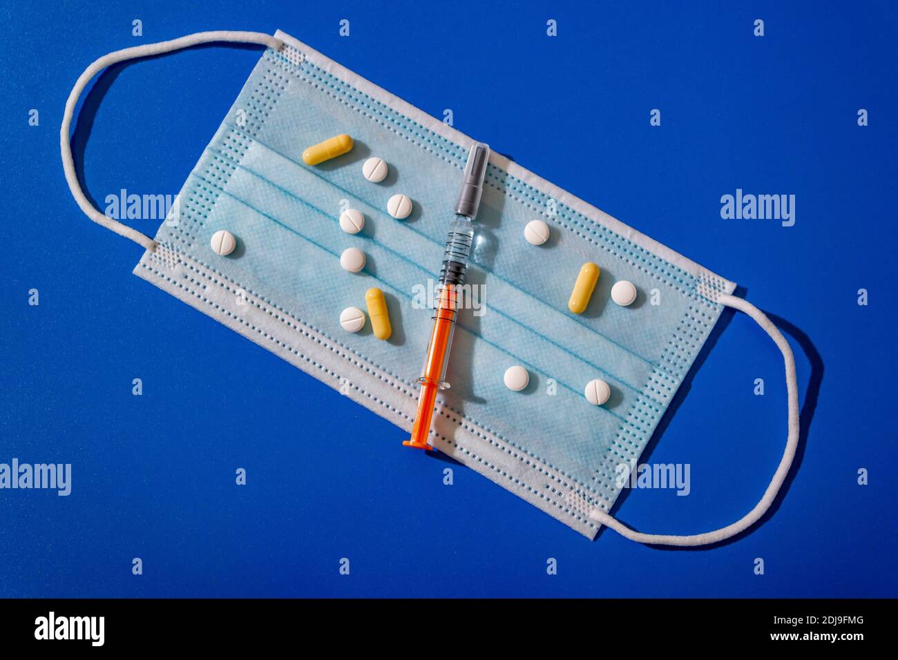 Medizinische Gesichtsmaske, Tabletten, eine Spritze, die auf einem blauen Hintergrund liegt.Coronavirus-Krankheit oder Corona-Virus-Konzept. Stockfoto