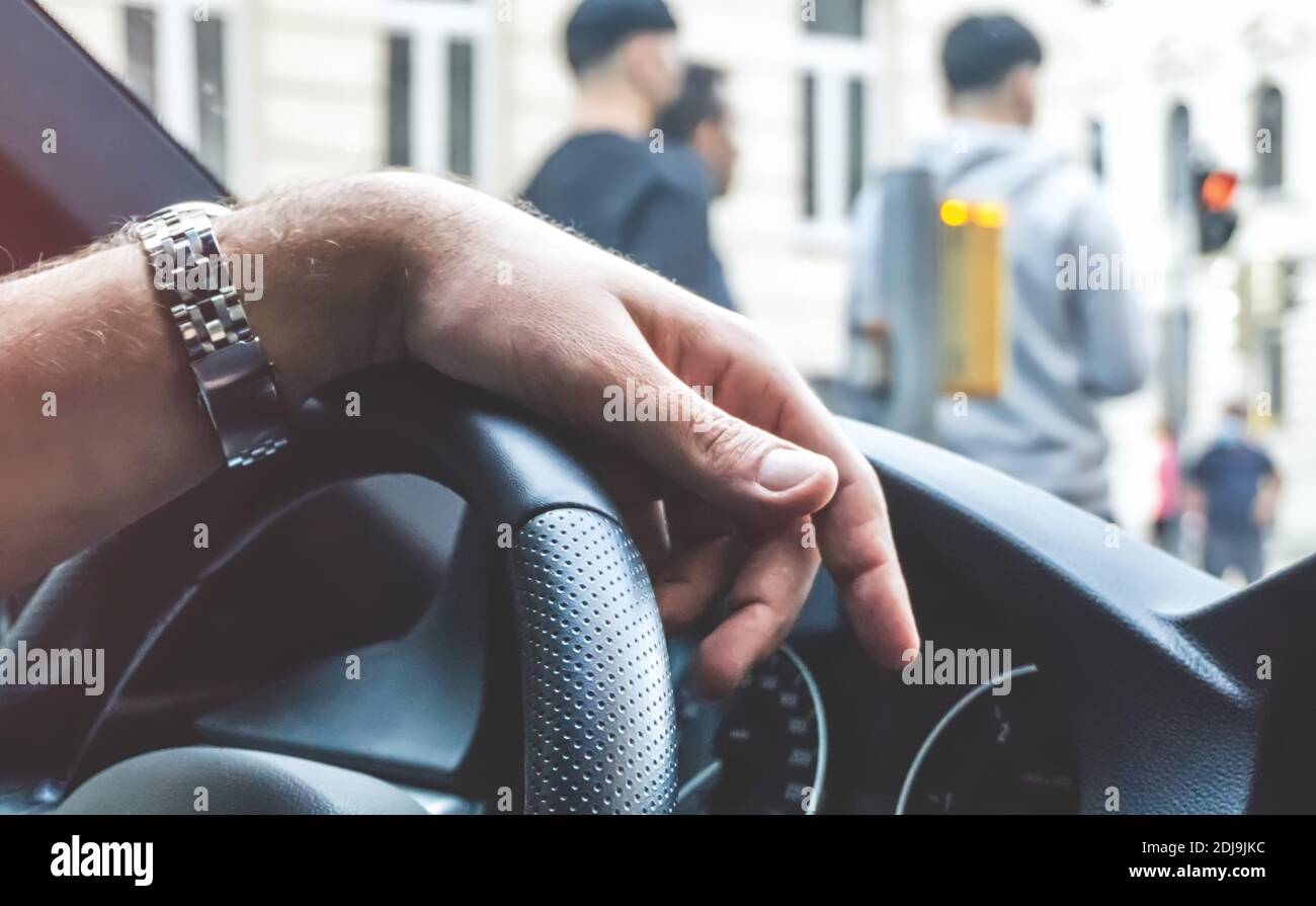 Nahaufnahme eines männlichen Hands am Lenkrad in einem Modernes Auto gegen überfüllte Stadt-Szene Stockfoto