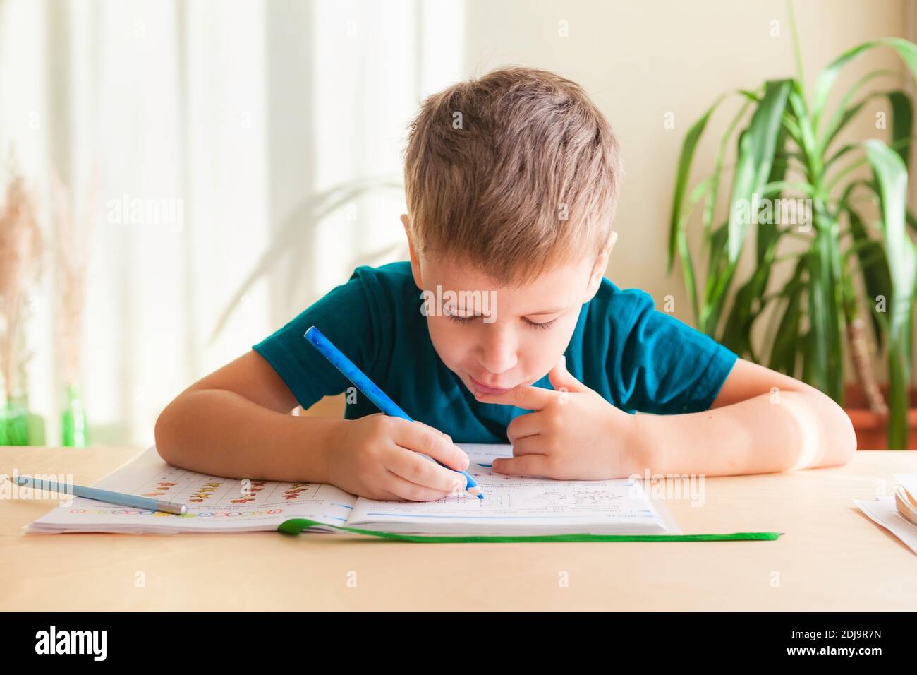7 Jahre alter Schuljunge, der Matheunterricht am Schreibtisch macht. Homeschooling Konzept, Fernunterricht Stockfoto