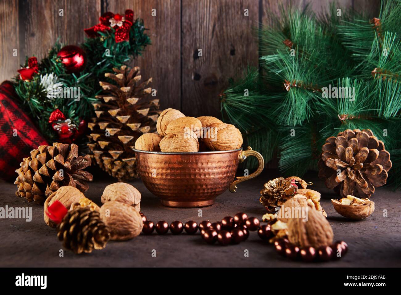 Walnüsse in einem Blechbecher, ganz und gehackt, neben der Füllung und Schalen. Präsentiert in einer Neujahrskomposition mit Tannenzapfen. Home Lagerung des Winters Stockfoto