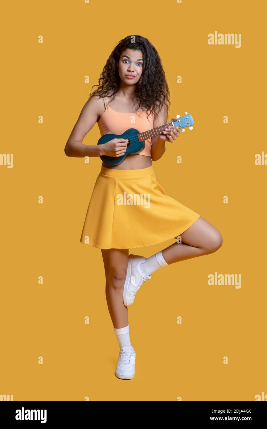 Hübsches junges Mädchen in gelben Kleidern mit Ukulele Stockfoto