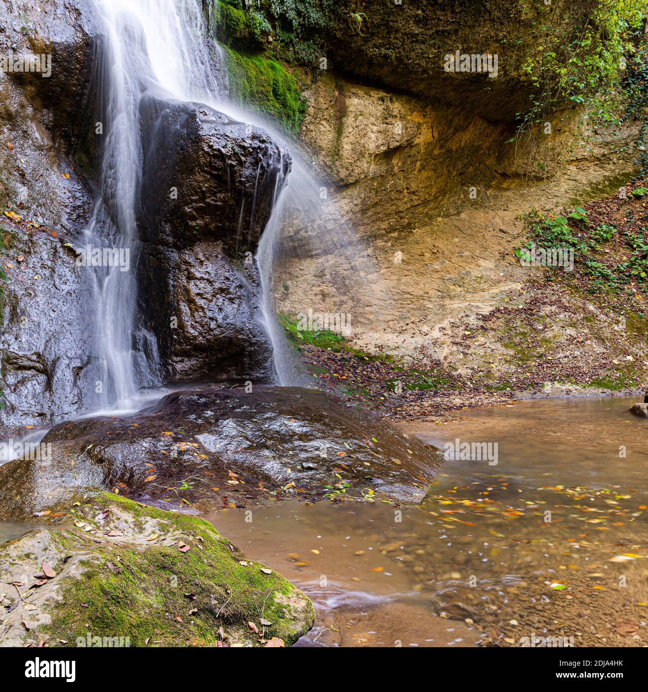 Langandauern Wasserfall über braunen und grünen Felsen. Stockfoto