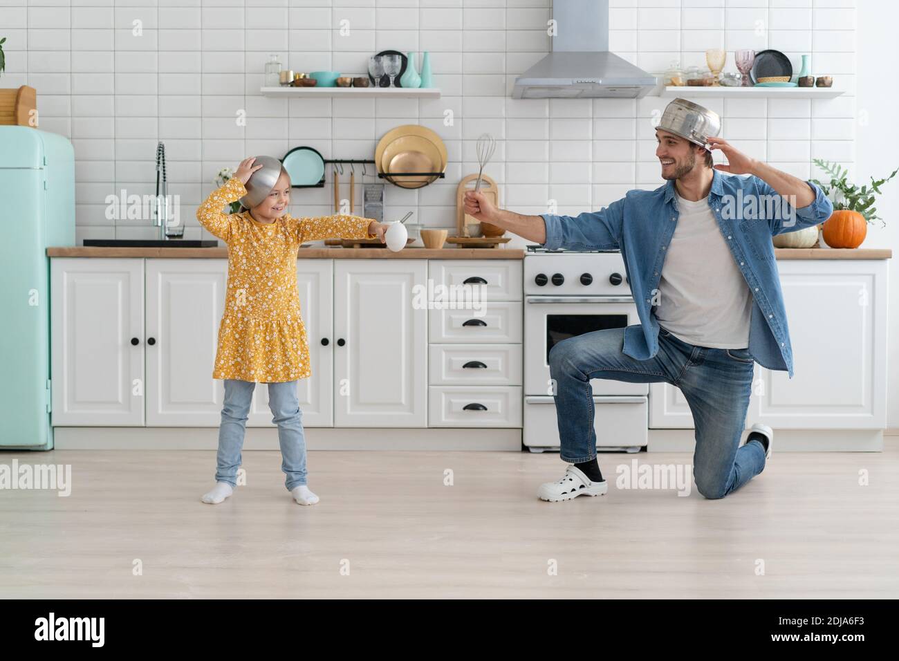 Kaukasischen Vater und Tochter genießen Schlacht lustige Aktivität in der Küche Verbringen Sie aktive Zeit zusammen am Wochenende zu Hause Stockfoto