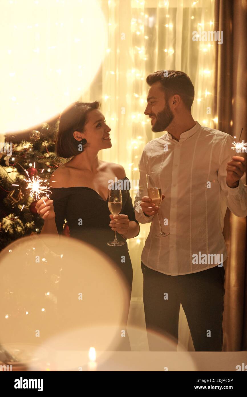 Anhänglich junges Paar stehend mit brennenden Wunderkerzen und Flöten und Einander betrachten und gemeinsam das neue Jahr begrüßen Stockfoto