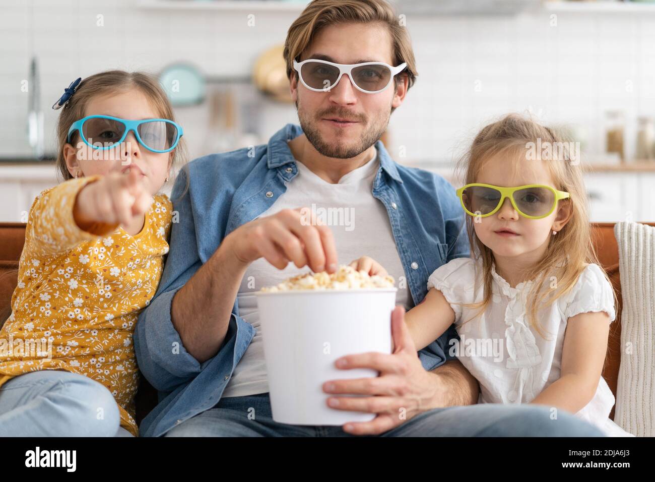 Glückliche Familie, die zu Hause Fernsehen und Popcorn essen. Stockfoto