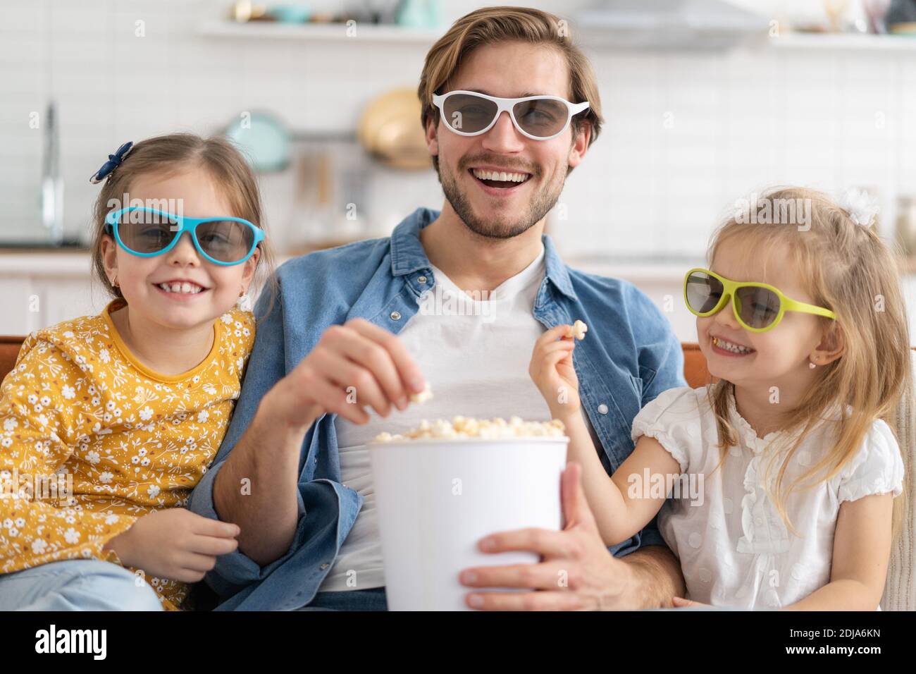 Glückliche Familie, die zu Hause Fernsehen und Popcorn essen. Stockfoto