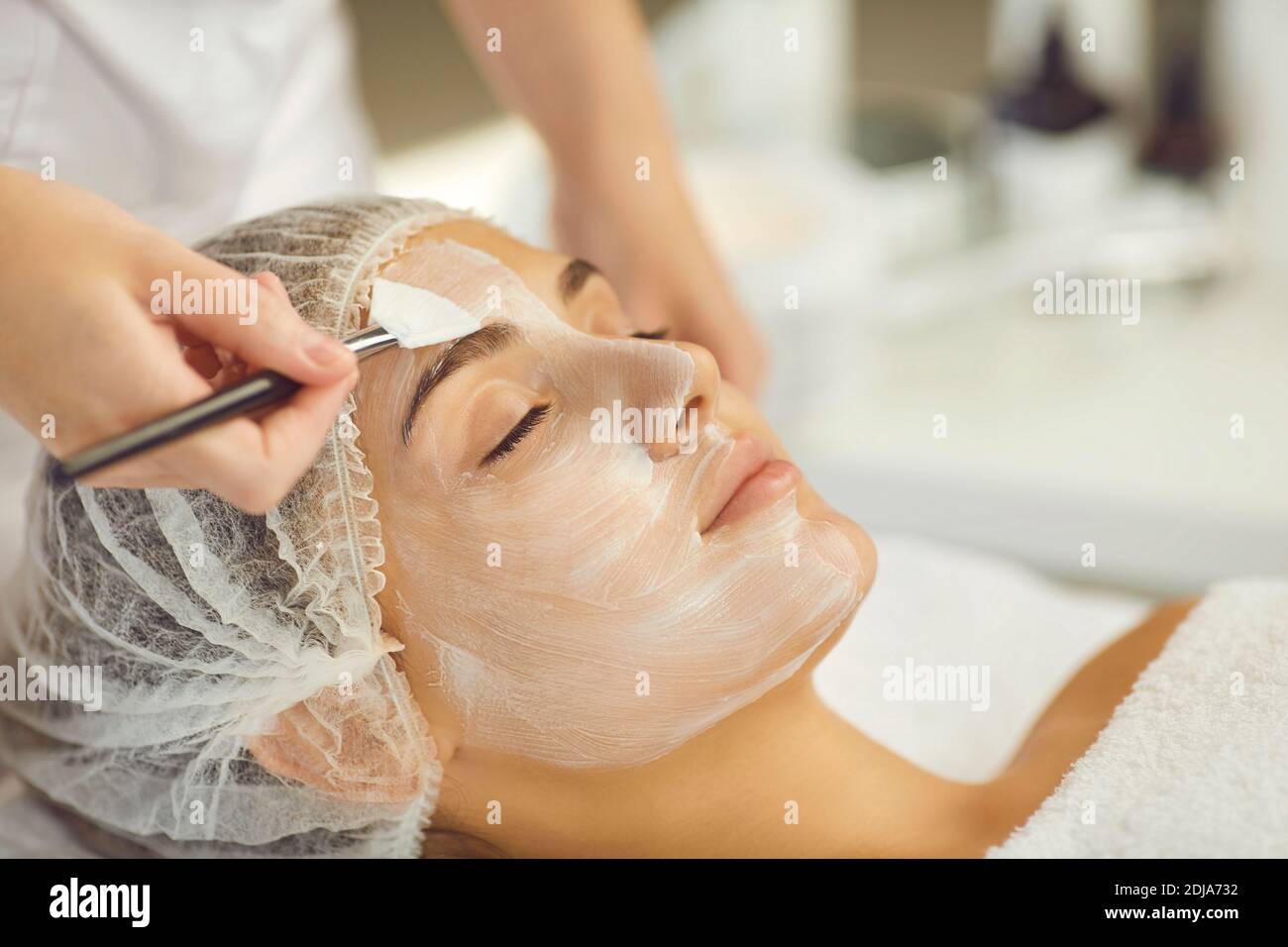 Entspannende Frauen Gesicht bekommen Verfahren der Anwendung feuchtigkeitsspendende Maske mit Bürste Stockfoto