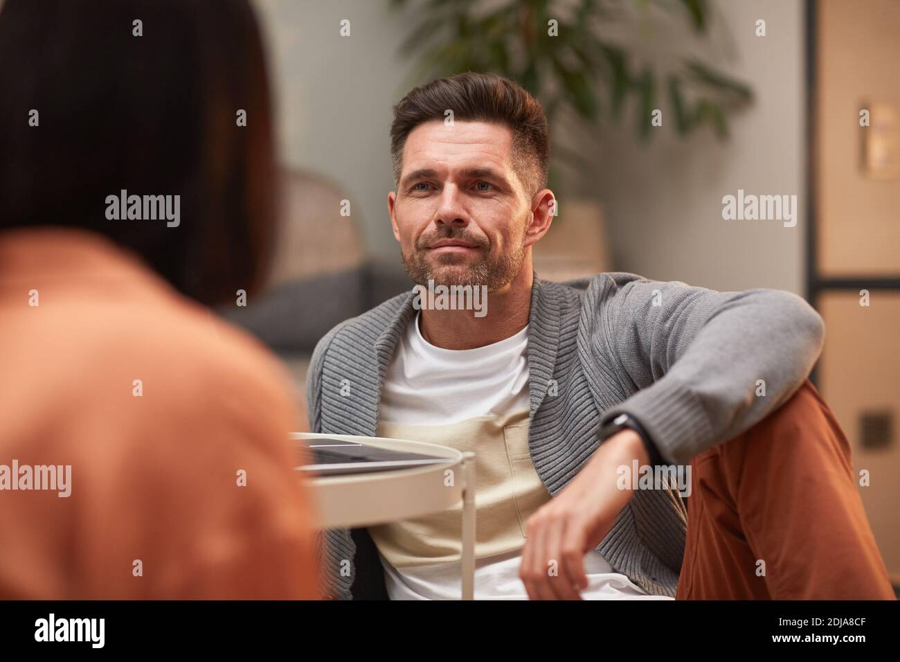 Portrait von schönen reifen Mann Blick auf Frau, während auf dem Boden in der modernen Wohnung sitzen und genießen Abend zusammen, kopieren Raum Stockfoto