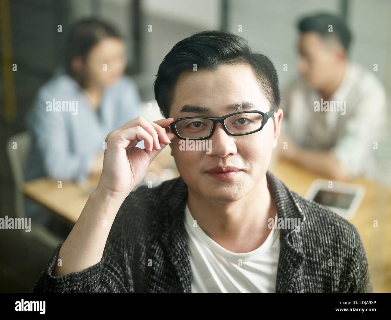 Junge asiatische Kleinunternehmer Blick auf Kamera lächelnd Stockfoto
