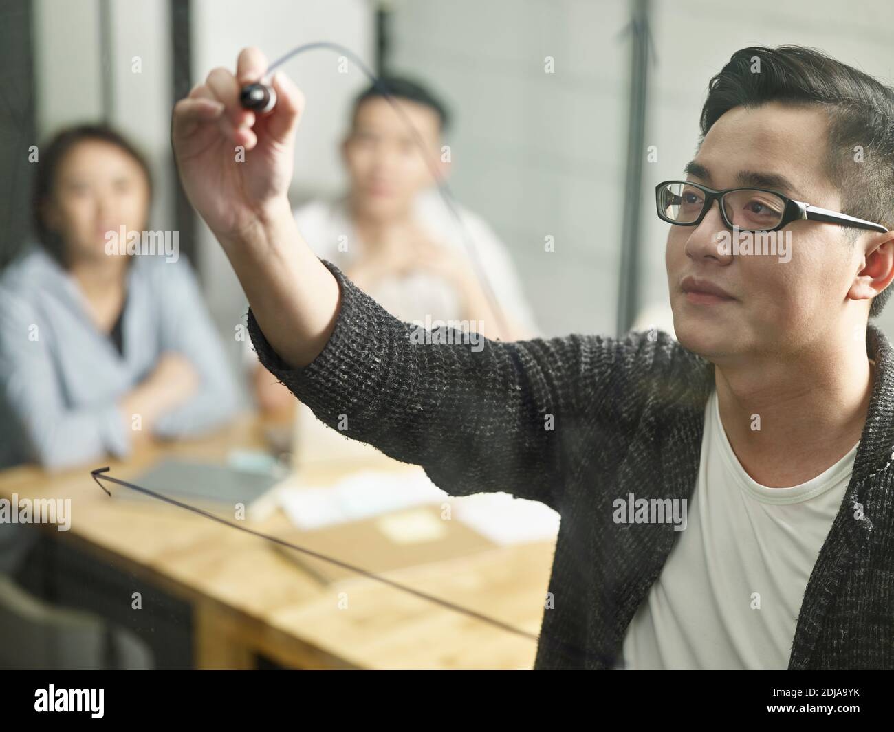 Junge asiatische kleine Firma Geschäftsmann Treffen mit Kollegen Zeichnung Eine Kurve auf Glas Stockfoto