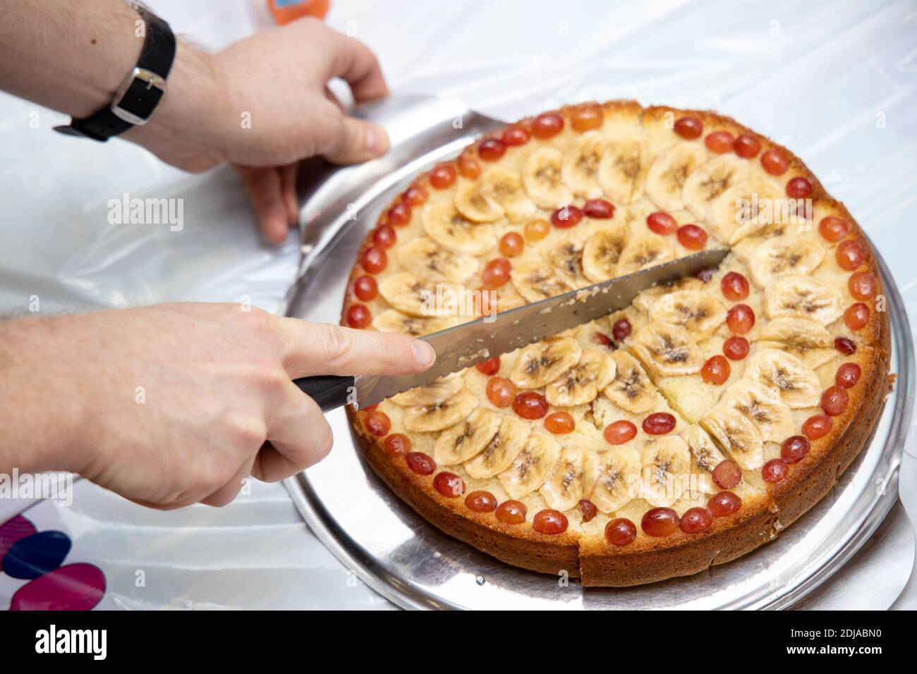 Mann schneidet hausgemachten Kuchen liegen auf runden Brett in Stücke mit Messer. Stockfoto