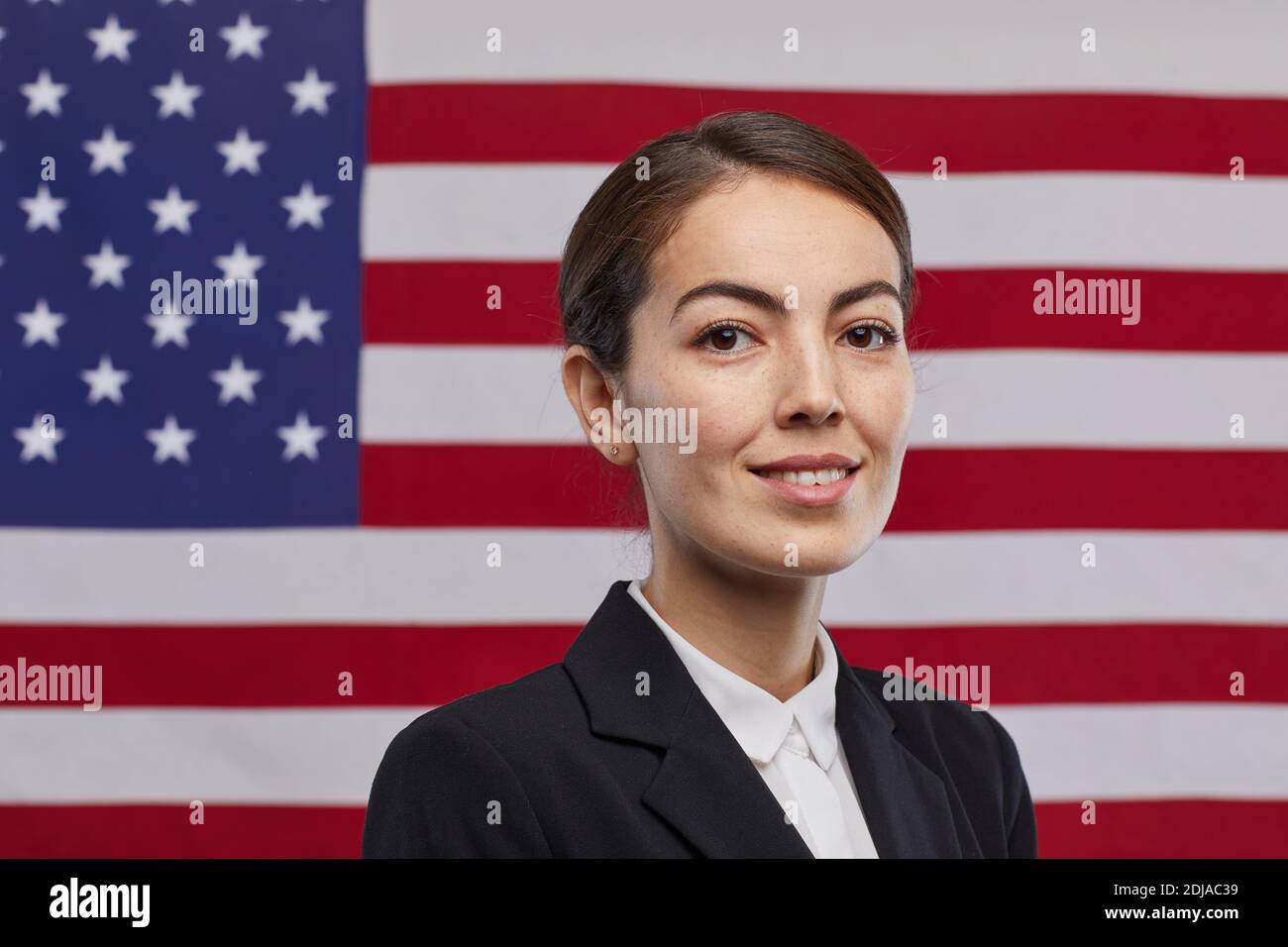Porträt einer lächelnden Politikerin, die vor dem Hintergrund der USA-Flagge auf die Kamera schaut, Kopierraum Stockfoto