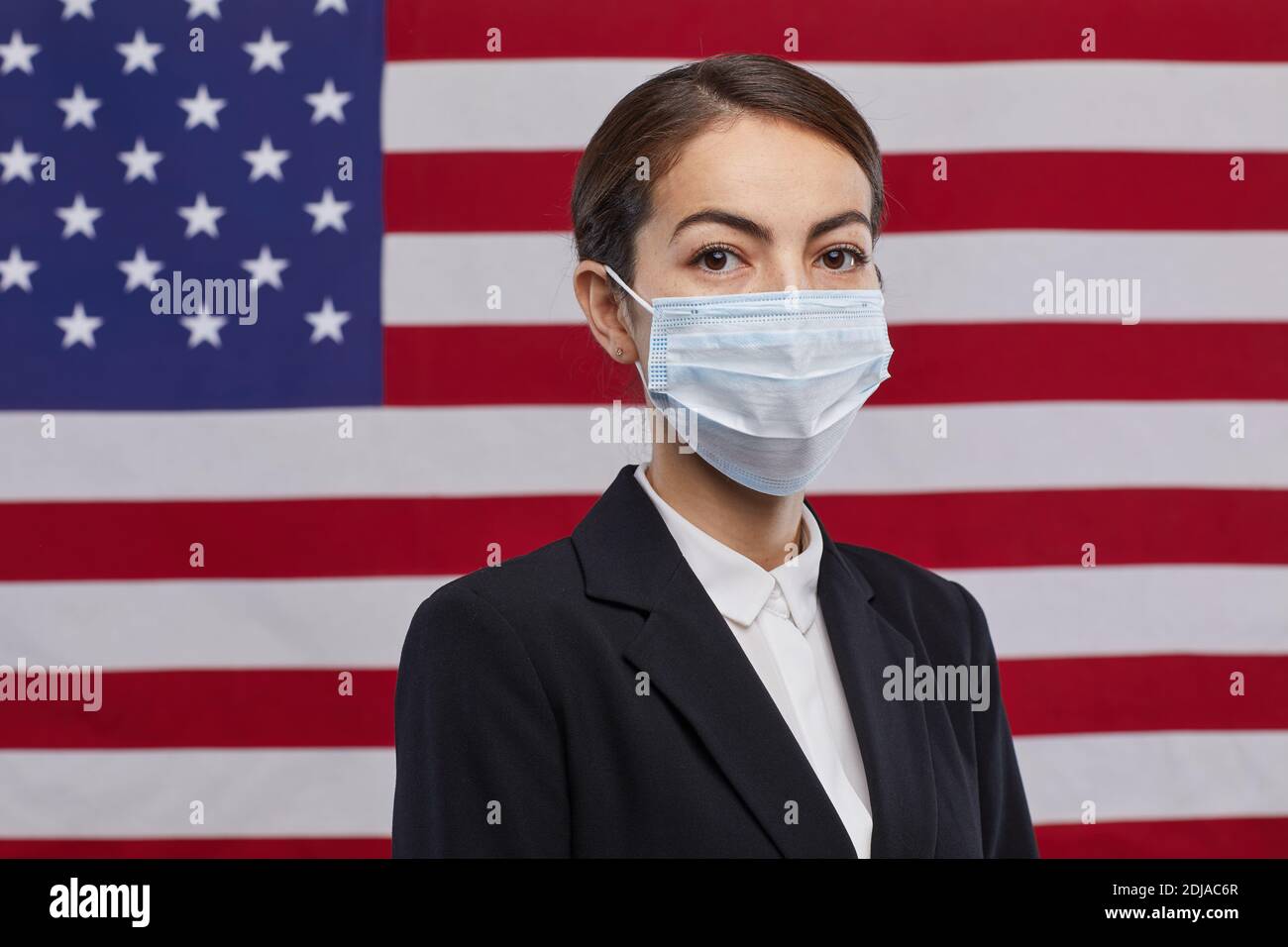 Porträt einer Politikerin in Maske und Blick auf die Kamera, während sie vor US-Flagge Hintergrund, kopieren Raum Stockfoto