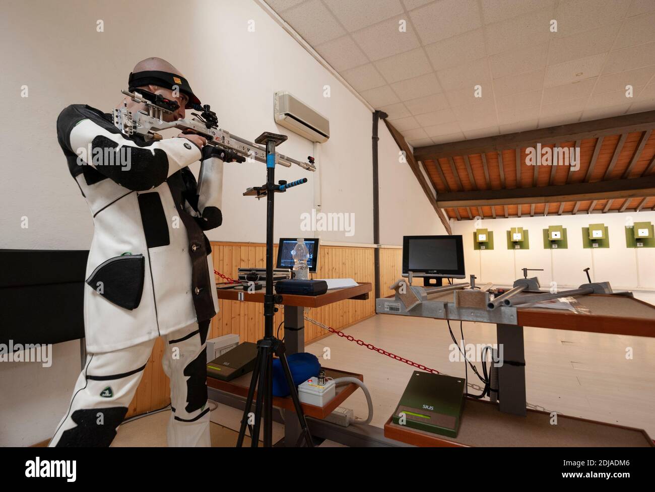 Professioneller Schütze mit sportlichem Luftgewehr und technischer Ausrüstung, während des Trainings auf dem Schießstand. Elektronisches Zielsystem. Stockfoto