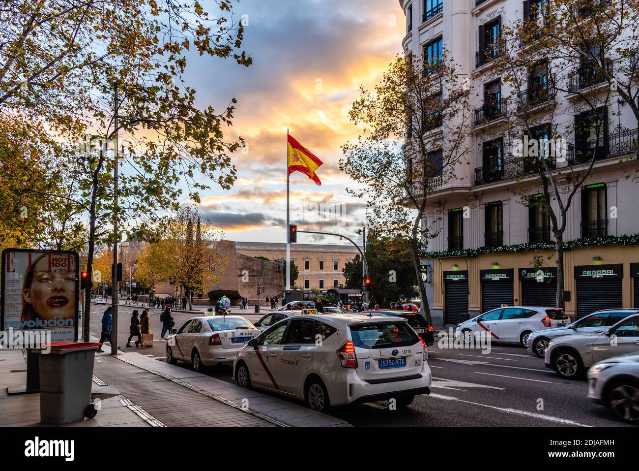 Madrid, Spanien - 6. Dezember 2020: Blick auf die Serrano-Straße mit der großen spanischen Flagge auf der Plaza de Colon in der Abenddämmerung im Stadtteil Salamanca. Stockfoto
