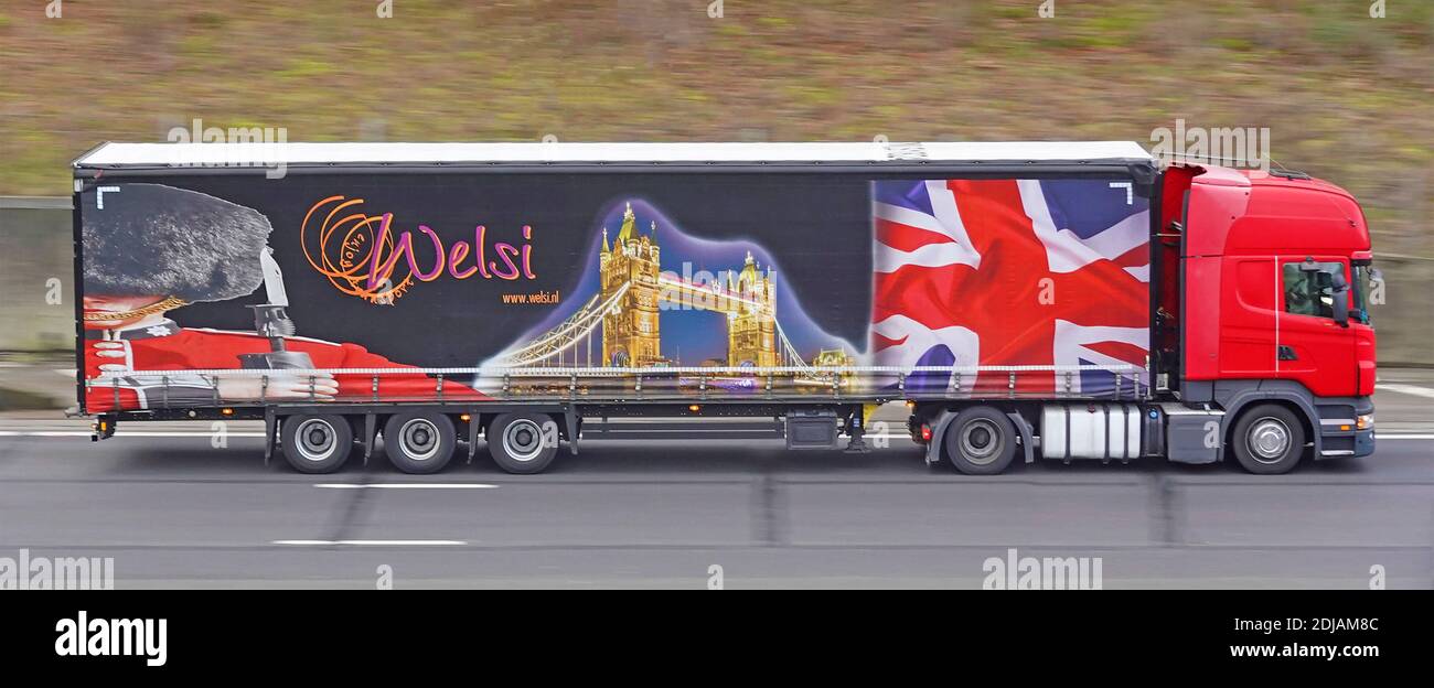 Ein roter LKW & bunte Grafiken auf Seitenvorhang Des niederländischen Welsi internationalen Transport Business-Trailer zeigt London Szenen Auf der britischen Autobahn Stockfoto