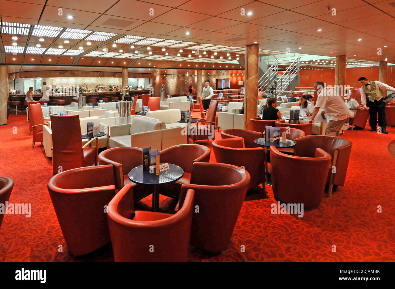 Rot-weiße Möbel, Stühle und Tische, abends drinnen Trinken Lounge Bar Kellner Passagiere Innenraum Kreuzfahrtschiff Liner Kreuzfahrt Persischer Golf Stockfoto