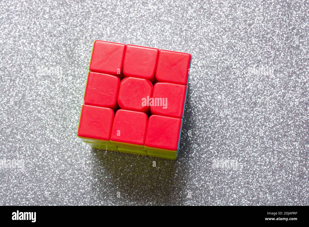 Ein gelöster Rubik-Würfel auf einer grau glänzenden Oberfläche - Problemlösungskonzept Stockfoto
