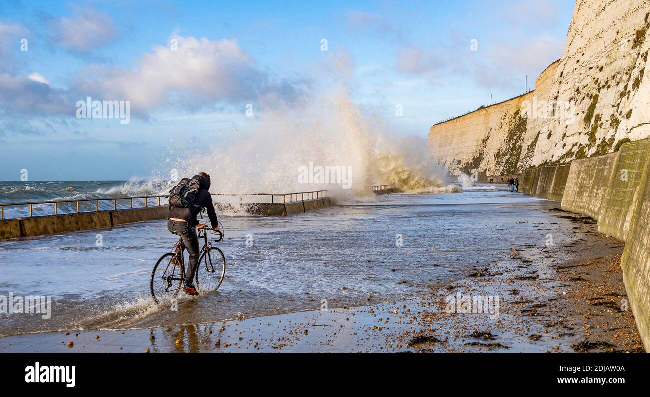 Brighton UK 14. Dezember 2020 - EIN Radfahrer pflügt durch das Wasser, während die Wellen an einem windigen Tag bei Saltdean undercliff Walk an der Strandpromenade nahe Brighton bei Flut einstürzen. Die Wettervorhersage ist für stärkere Winde und Duschen, um über Teile von Großbritannien zu verbreiten, aber mit Temperaturen, die wärmer als in den letzten Tagen sind : Credit Simon Dack / Alamy Live News Stockfoto