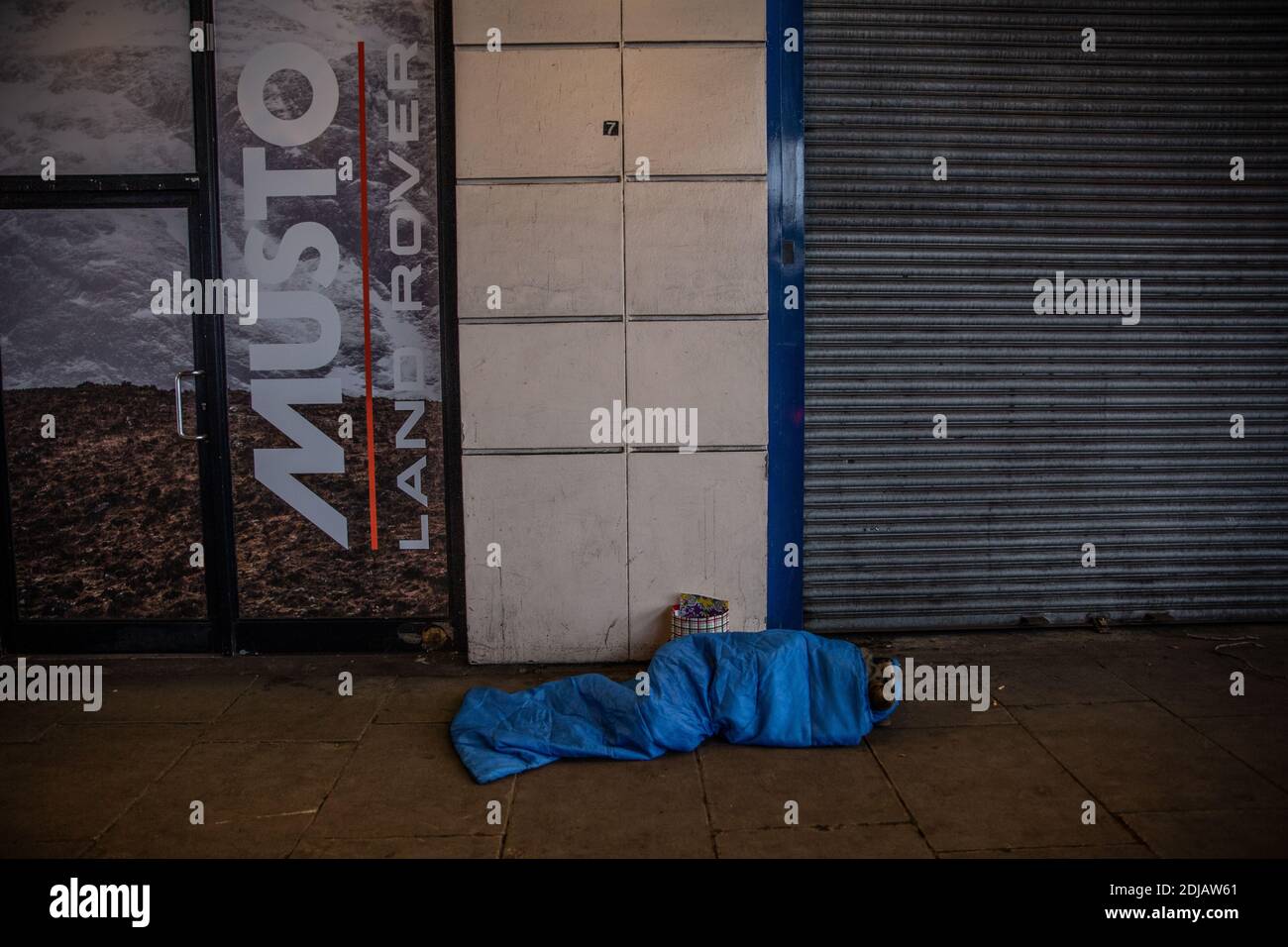 Rauer Schläfer liegt in einem Schlafsack auf dem kalten Bürgersteig entlang des Victoria Embankment während eines Wintertages in der Hauptstadt London, England, Großbritannien Stockfoto