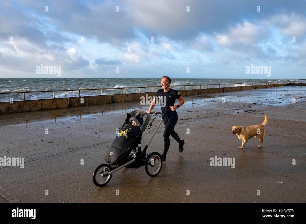 Brighton UK 14. Dezember 2020 - EIN Läufer genießt das windige Wetter entlang Saltdean undercliff Walk an der Küste in der Nähe von Brighton heute bei Flut. Die Wettervorhersage ist für stärkere Winde und Duschen, um über Teile von Großbritannien zu verbreiten, aber mit Temperaturen, die wärmer als in den letzten Tagen sind : Credit Simon Dack / Alamy Live News Stockfoto