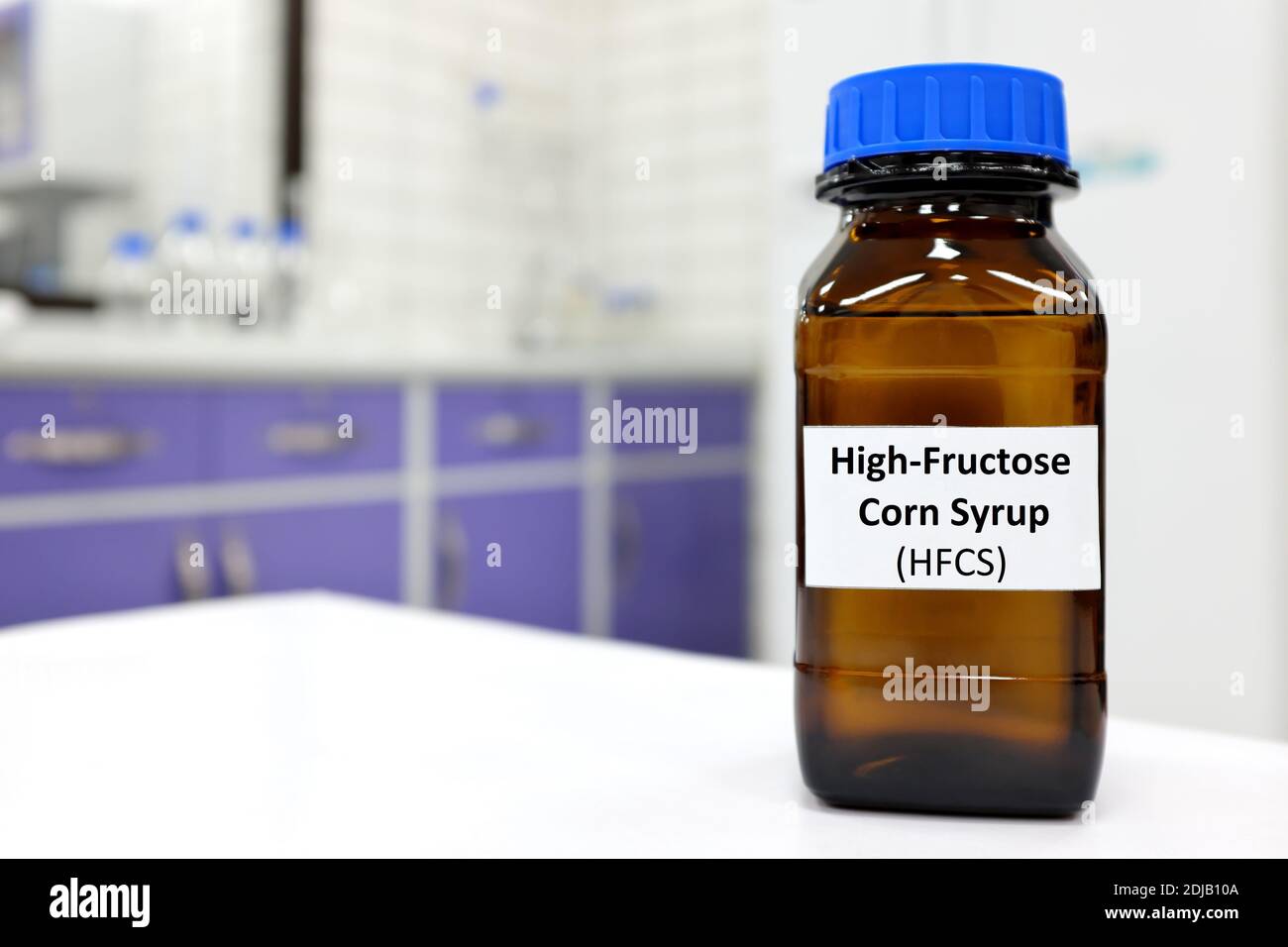Selektiver Fokus von High-Fructose-Maissirup oder hfcs Lebensmittel- und Getränkesüßstoff in dunkelbrauner Glasflasche im Labor. Stockfoto
