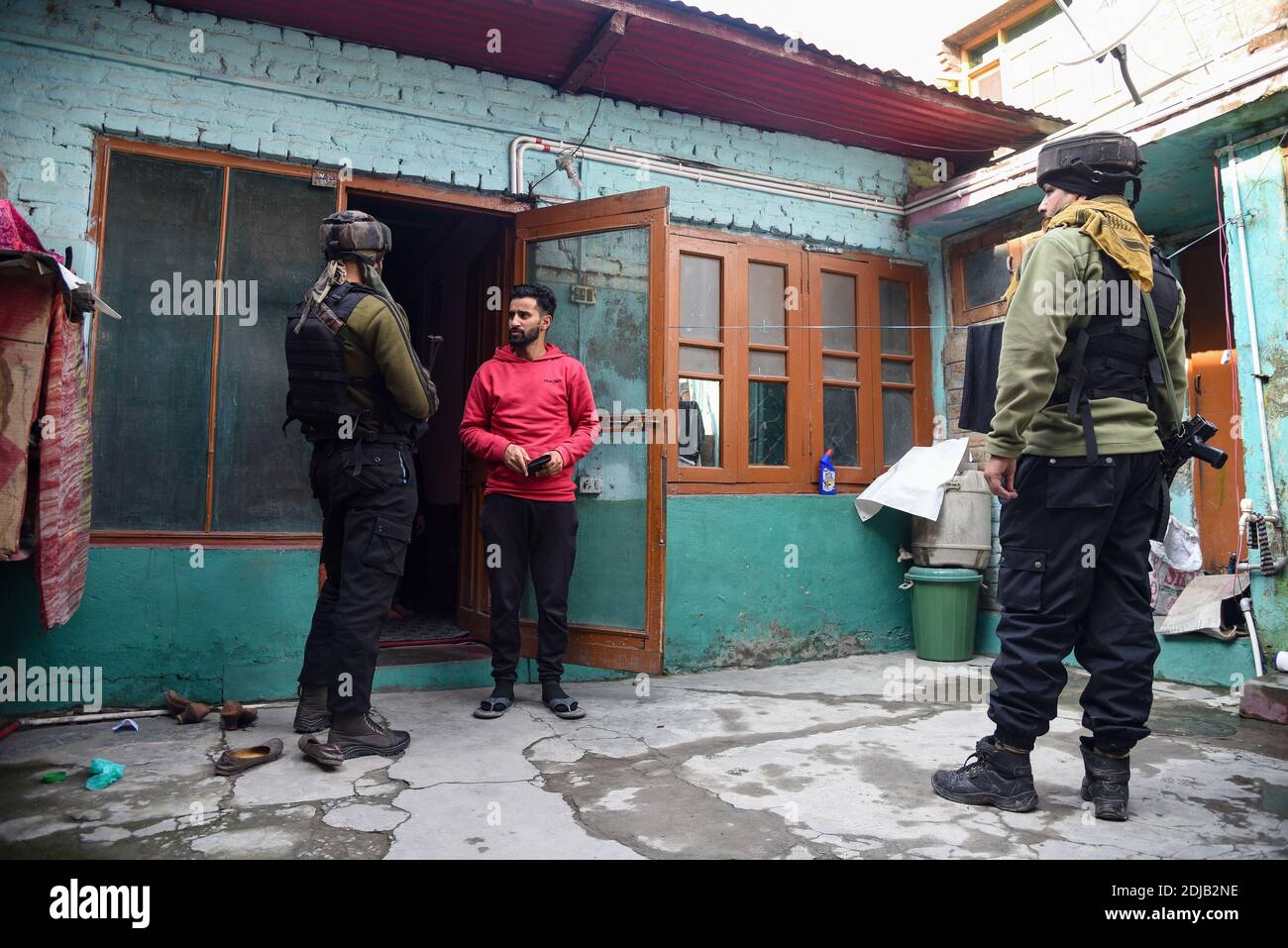 Indische Streitkräfte befragen einen Zivilisten in der Nähe des Angriffs in Srinagar.EIN Polizist wurde getötet, nachdem unbekannte Schützen auf ihn in der Residenz des politischen Parteiführers Parvaiz Bhat in der Gegend von Natipora der Stadt Srinagar abgefeuert wurden, sagten Polizeibeamte. Stockfoto