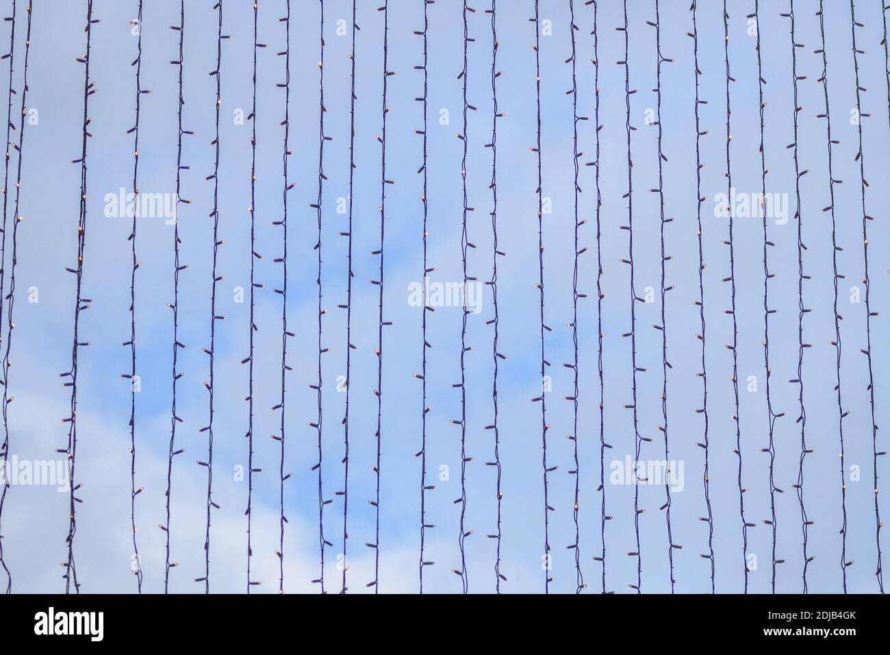 Weihnachtliche Hintergründe von Lichtersträngen, die an einem blauen hängen Himmel in der Nähe für Feiertagsfeiern Stockfoto