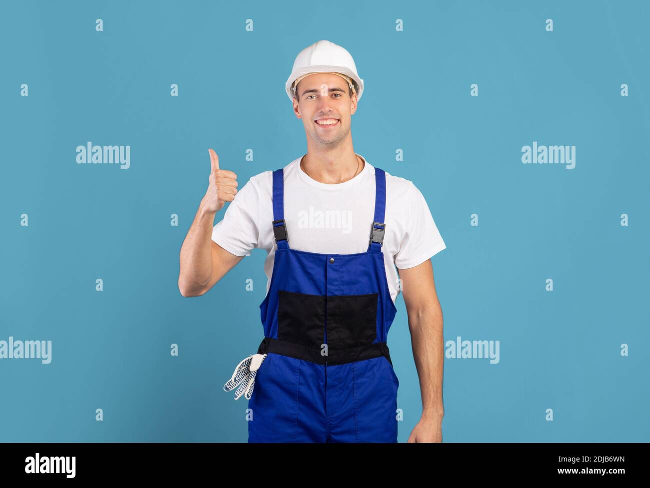 Portrait Von Young Maintenance Worker In Hardhat Und Coveralls Showing Daumen Hoch Stockfoto