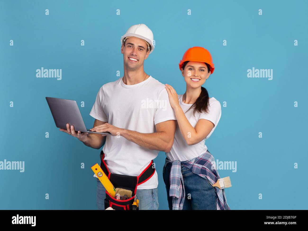 Portrait Von Glücklichen Mann Und Frau In Harten Hüten Mit Laptop-Computer Stockfoto