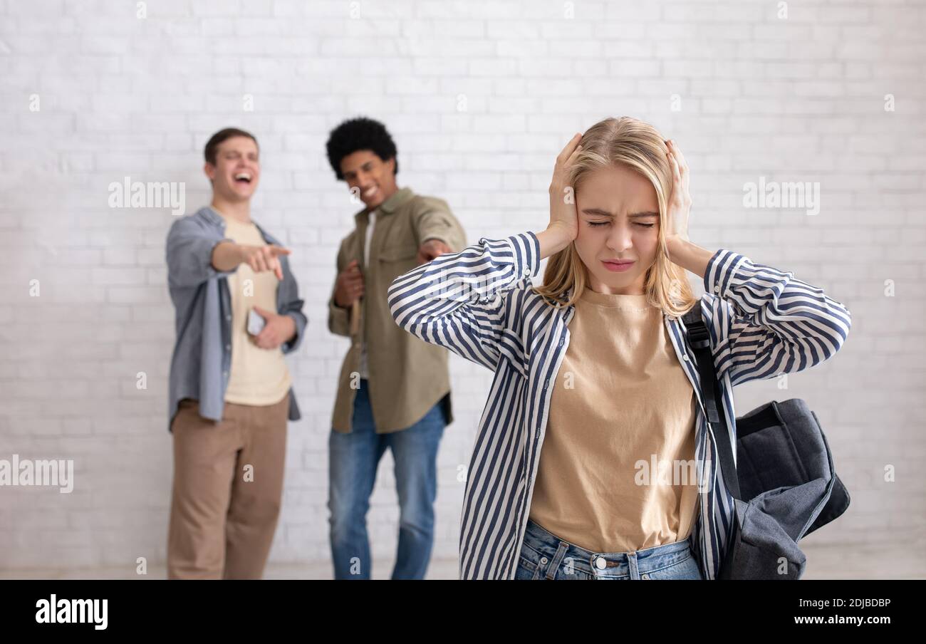 Mobbing und Beziehungen zu Kollegen. Konzentrieren Sie sich auf blonde Teen Dame mit Rucksack bedeckt ihre Ohren Stockfoto