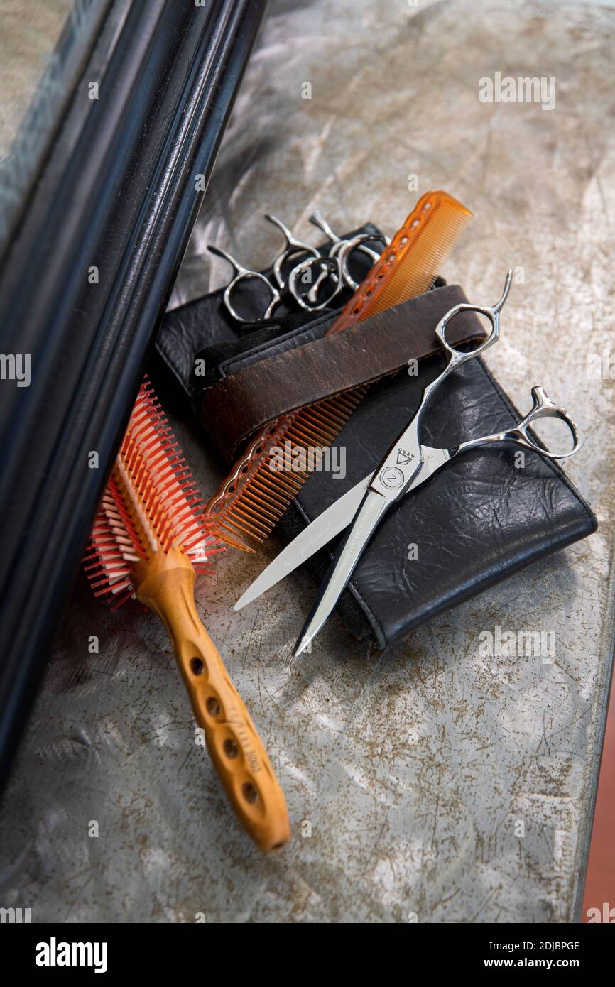 Professionelle Friseurwerkzeuge: Kamm, Haarbürste, Schere und Lederetui auf einem Regal vor dem Spiegel angezeigt Stockfoto