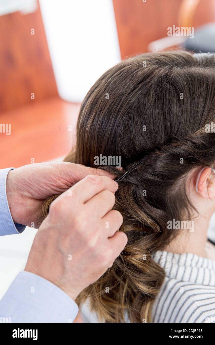 Frau, Klientin, die ihre Haare in einem Friseursalon schneiden lässt. Friseur, Mann, Haarnadeln setzen Stockfoto