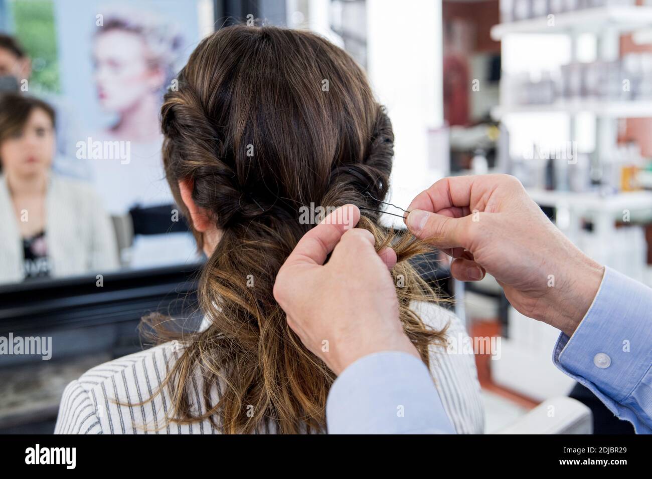 Frau, Klientin, die ihre Haare in einem Friseursalon schneiden lässt. Friseur, Mann, Haarnadeln setzen Stockfoto
