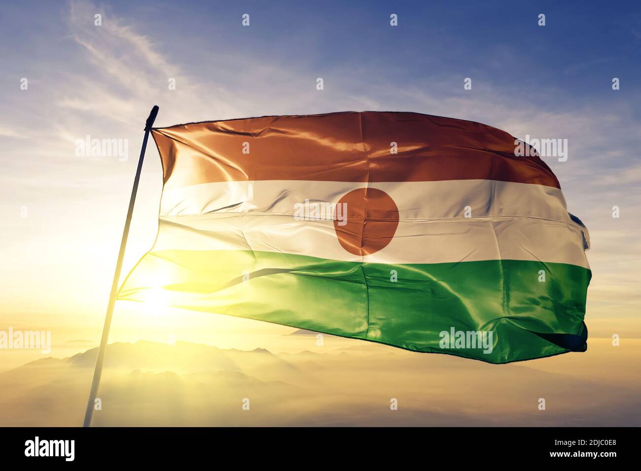 Niger Flagge winkt auf der Oberseite Sonnenaufgang Nebel Stockfoto
