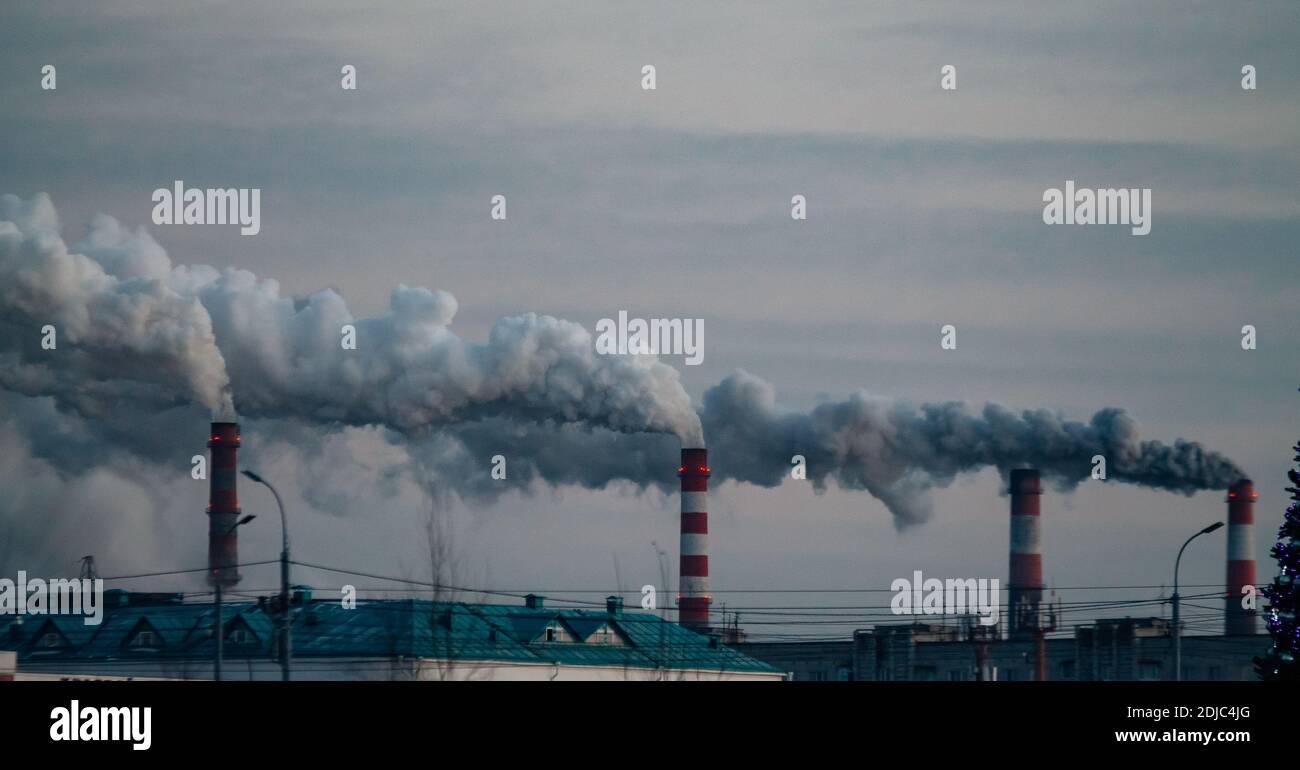 Industriekamine mit Rauch auf dem grauen Himmel Hintergrund. Smokestack Verschmutzung in der Luft als Umweltproblem Stockfoto
