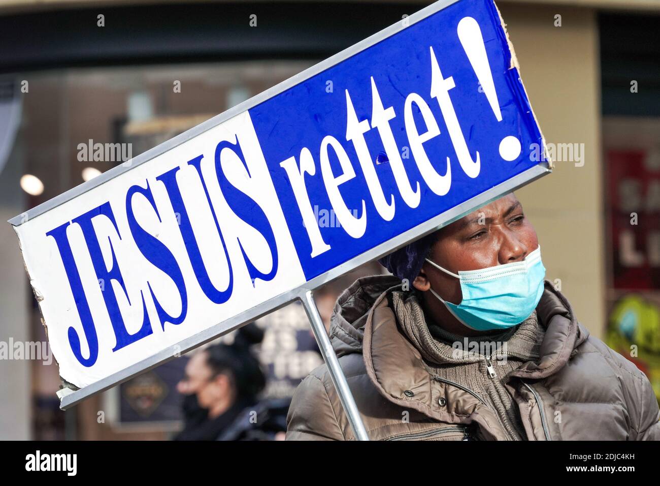 Eine Frau mit Mund- und Nasenschutz trägt ein Zeichen, das Jesus RETTET liest! Durch die Fußgängerzone Westenhellweg in Dortmund --- eine Frau mit Mund-Nasenschutz tragt während der Corona-Zeit ein Schild mit der Aufschrift JESUS RETTET! Durch die Fußgängerzone Westenhellweg in Dortmund Stockfoto