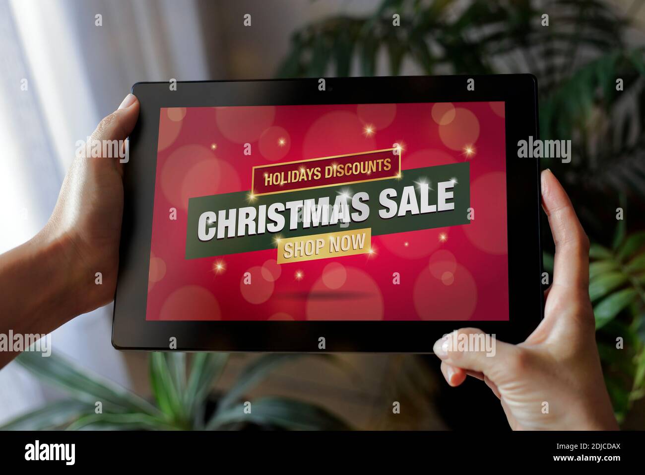Weihnachtsverkauf Werbung auf dem Bildschirm des Tablets. Frau hält einen Pad-Computer mit Ankündigung von Weihnachten auf dem Display. Stockfoto