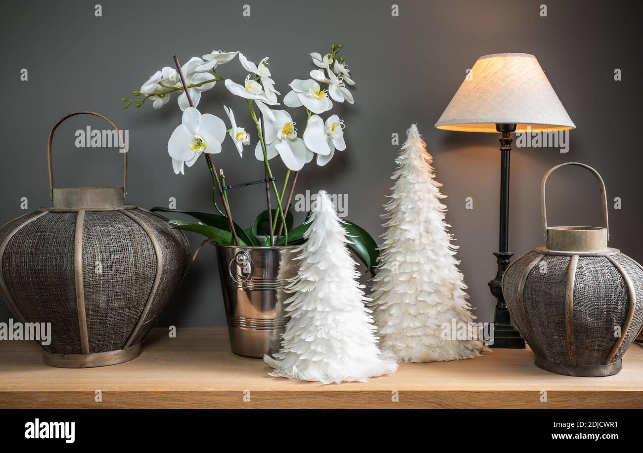 Stillleben mit weißer Orchidee, Lampe, dekorativen Bäumen und Kerzenhaltern. Stockfoto