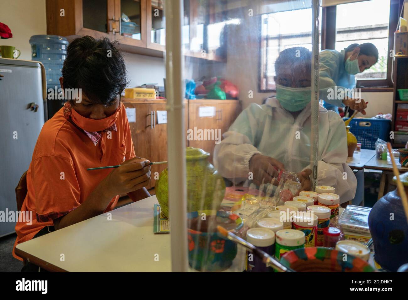 BALI/INDONESIA-OCT 23 2020: Kinder mit körperlichen Behinderungen lernen Farbe. Sie werden von einem Therapeuten begleitet. Sie benutzen Masken und Hamzat Stockfoto