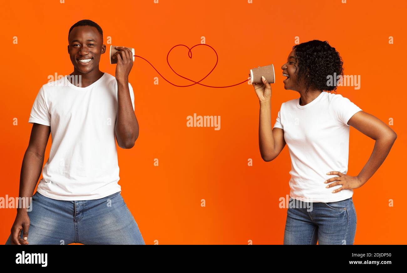 Junge schwarze Paar mit können Sie auf orange Hintergrund Stockfoto