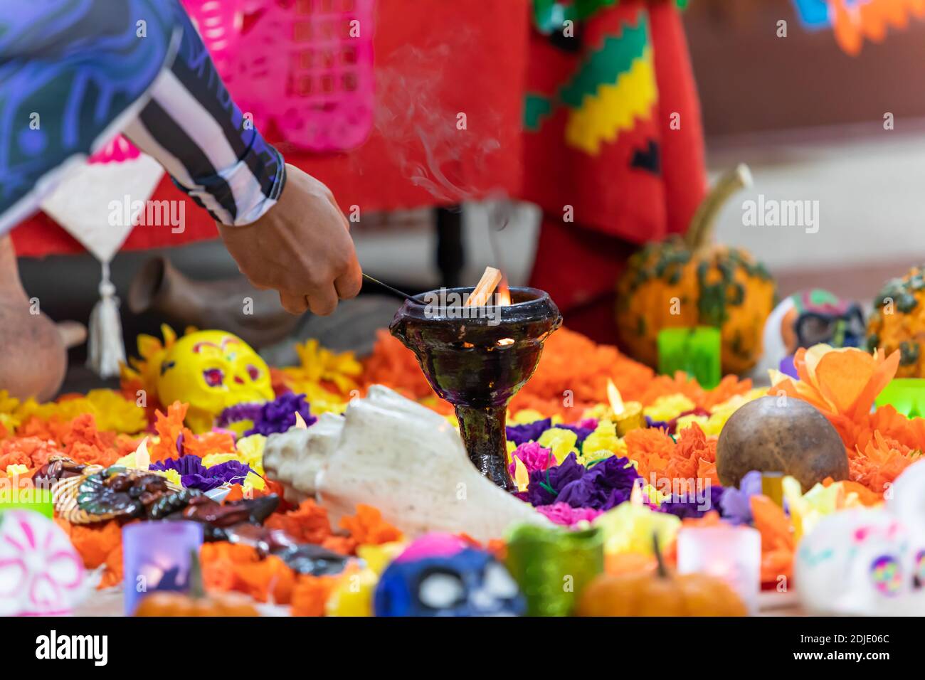 Selektiver Fokus der männlichen Hände, die Kerze zwischen dekorierten liegen anzünden catrina und campasuchil während der Tribute während Dia de los muertos Stockfoto